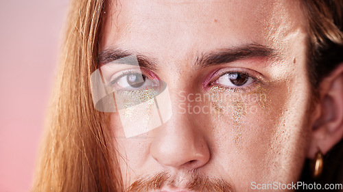 Image of Makeup, eyes and portrait of gen z man with serious expression on face with pink background. Gold, glitter tears and art, zoom on eye cosmetics on non binary, transgender or gender neutral lgbt model