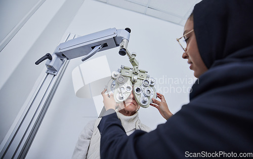 Image of Vision exam, eyes and senior woman with optometrist in clinic for test, eyesight and optical assessment. Optometry, healthcare and Muslim optician with patient for phoropter, lens and medical machine