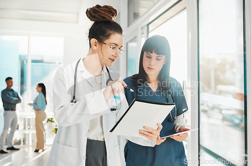 Image of Woman, doctor and team with document in planning, strategy or ideas by window for healthcare notes at clinic. Female doctors or nurse checking paperwork together for medical information at hospital