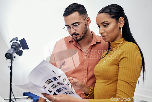 Image of Documents, teamwork or planning with a photographer and model talking in a studio for creative production. Collaboration, designer or fashion with a designer man and woman at work on a magazine shoot