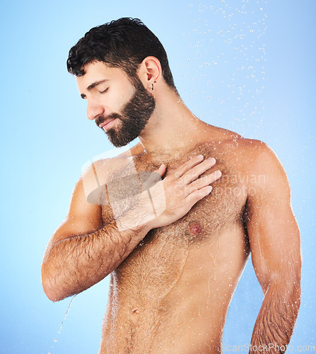 Image of Body care, shower and man in studio for wellness, hygiene and skincare against blue background. Cleaning, chest and male model relax in luxury, water splash and beauty routine isolated in a bathroom