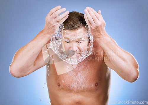 Image of Man, face and water splash in skincare hygiene for natural sustainability against a blue studio background. Male washing for clean health and wellness in self love or care for facial treatment