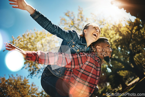 Image of Young couple, flying and piggyback in park, summer and date together in sunshine, happiness or nature. Happy man carrying woman in garden of love, care and freedom to play, smile or diversity partner