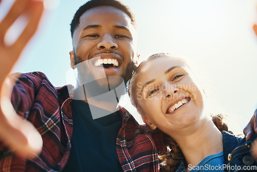 Image of Interracial love, couple selfie and laughing at funny joke outdoors, having fun or bonding in low angle. Comic smile, romance portrait and black man and woman take pictures for happy memory together