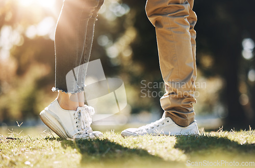 Image of Couple, legs and feet standing on grass field for love, affection or bonding together in nature. Leg of woman raising foot for height with man for loving care, touch or embrace in the park outdoors