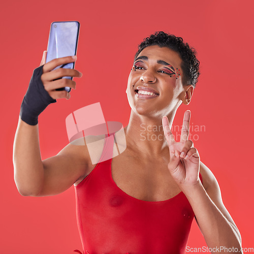 Image of Selfie, queer and gay man peace sign gesture for social media update isolated against a studio red background. LGBTQ, non binary and gen z fashion model with online photo for the internet