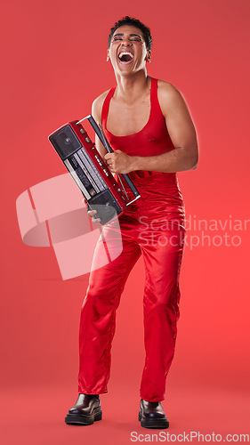 Image of Radio, laughing and red background with a gen z man in studio listening to music for carefree fun. Transgender, non binary and laughter with a young androgynous or gay person posing for inclusion