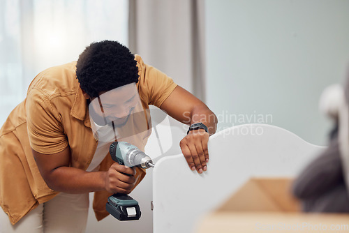 Image of DIY, drill and crib with a black man in his house to build furniture in the baby bedroom or nursery. Family home, handyman and cot with a father in a room building a bed for his newborn kid