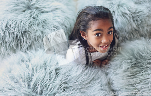 Image of Relax, happy and portrait of a child with pillows in her modern bedroom in her home. Happiness, smile and girl kid resting, having fun and being playful with fluffy blankets in her room at a house.