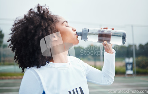 Image of Sports, black woman and drinking water at court during training, workout and sport exercise outdoors. Fitness, thirsty and girl with bottle for wellness, hydration and recovery during practice