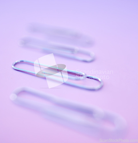 Image of Paperclip, filing and organization for documenting or attachment in studio on a purple background. Business, office and stationery with a metal clip for file or storage purposed on a color surface