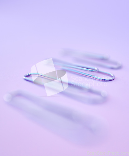 Image of Row, paper clips and office stationery for paperwork in a studio with a purple background. Work supplies, equipment and steel wire clips in a line to organize or hold document, report or form sheets.