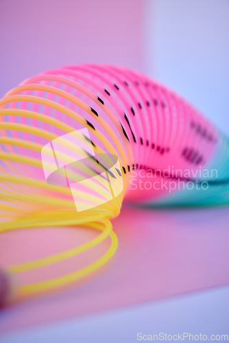 Image of Rainbow, slinky toy and color spiral in studio for neon background for flexible, abstract or creative vaporwave aesthetic wallpaper. Colorful plastic spring backdrop for art, relax and happiness