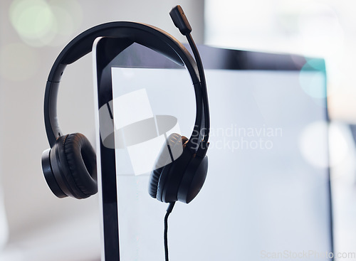 Image of Headset, computer and mockup screen in call center for desktop support, communication or telemarketing at office. Headphones, equipment or contact us technology and tools on monitor display at work