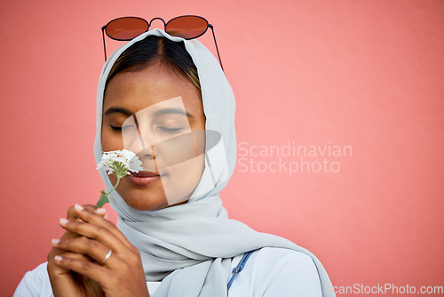 Image of Smelling, fresh and Muslim girl with a flower isolated on a pink background in a studio. Spring, peace and Islamic woman with the aroma of a calming plant for relaxation, stress relief and summer