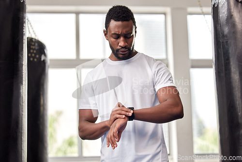 Image of Fitness, gym and black man with smart watch for time, health app or tracking wellness goals. Sports, training and serious male athlete using technology for monitoring workout or exercise targets.