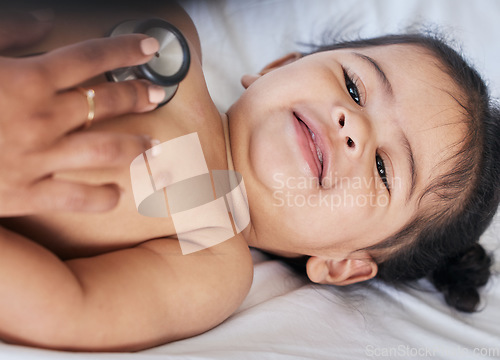 Image of Baby, stethoscope and health and medical doctor care for happy child heart, lungs and wellness. Face and smile of toddler girl kid on a hospital bed for growth and development check with pediatrician