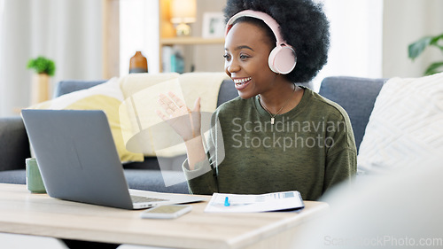 Image of Woman talking on videocall using laptop and headphones while waving hello to friends online. Student making notes while communicating and learning new language during online course or private lesson