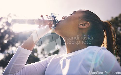 Image of Drinking water, fitness and running with a sports woman outdoor for a cardio or endurance workout. Training, exercise and wellness with a female athlete taking a drink for hydration on a break