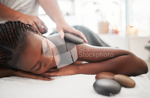 Image of Black woman, hot stone massage, spa with hands of masseuse, holistic and wellness with treatment. Health, peace of mind and zen, self care and rocks, stress relief for people and back skin detox