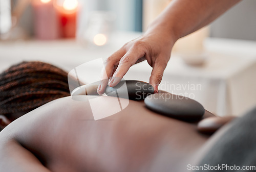 Image of Hot stone massage, spa and hand of masseuse, holistic care and wellness with black woman and treatment. Health, peace of mind and self care with zen, stress relief for people and back skin detox