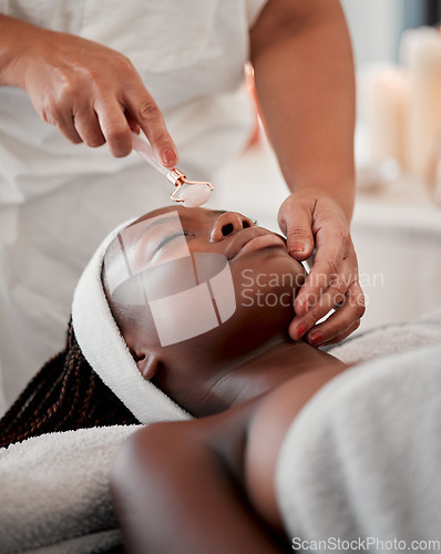 Image of Black woman, face roller and luxury spa treatment of a young female ready for facial. Skincare, rose quartz tool and wellness clinic with client feeling calm and zen from massage and dermatology