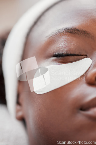 Image of Closeup, cosmetics and black woman, eye patch and skincare for beauty, wellness and luxury treatment. Zoom, Nigerian female client and lady applying skin mask, moisturize and organic facial for shine