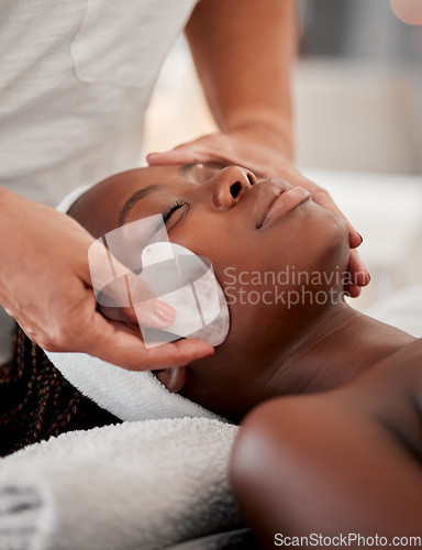 Image of Black woman face, relax and gua sha stone spa treatment of a young female with facial. Skincare, beauty and wellness clinic with client feeling calm and zen from massage and dermatology glow