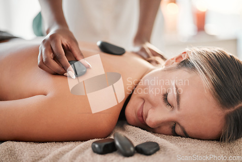 Image of Woman, hot stone massage and masseuse, hand and zen with holistic therapy and spa treatment for back. Calm, peace of mind and face, healing and stress relief with self care at wellness resort