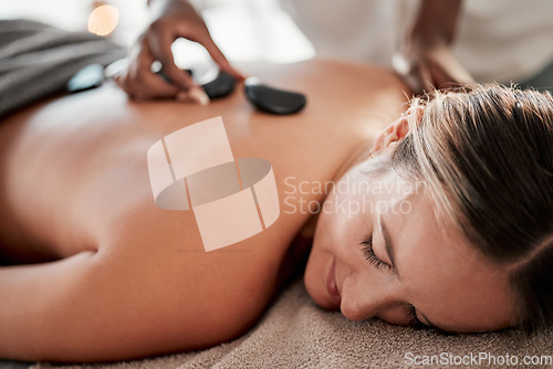 Image of Woman, hot stone massage and masseuse, hands and zen with holistic therapy and spa treatment for back. Calm, peace of mind and body care, healing and stress relief with self care at wellness resort