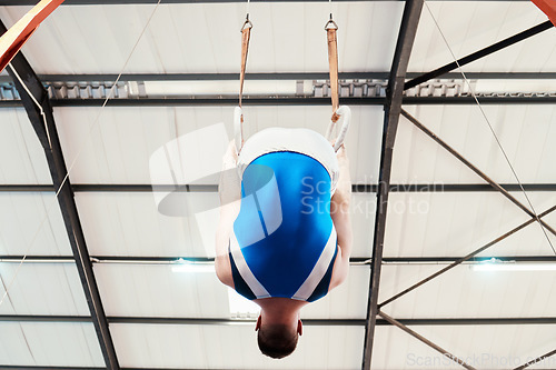 Image of Man, acrobat and gymnastics on rings in fitness for practice, training or workout performance at gym. Professional male gymnast hanging on ring circles for athletics, acrobatics or strength exercise