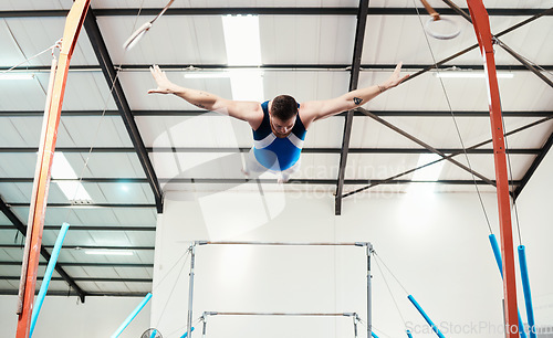 Image of Man, acrobat and gymnast flying off rings in fitness for practice, training or workout at gym. Professional male in gymnastics or performance for athletics, acrobatic or strength and balance exercise