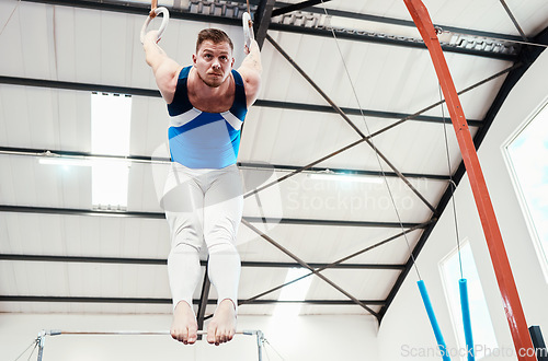 Image of Man, acrobat and gymnastics balance on rings in fitness for practice, training or workout at gym. Professional male gymnast hanging on ring circles for athletics, acrobatics or strength exercise