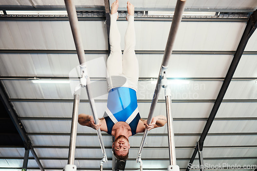 Image of Man, gymnast and upside down on poles in fitness for practice, training or workout at gym. Professional male acrobat in gymnastics holding body weight up on rail for athletics or strength exercise