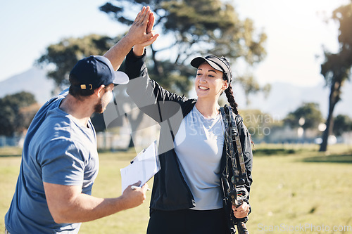 Image of Woman, archery and personal trainer high five in sports for partnership, success or celebration on the grass field. Happy sporty female smile and touching hand of male coach for archer sport training