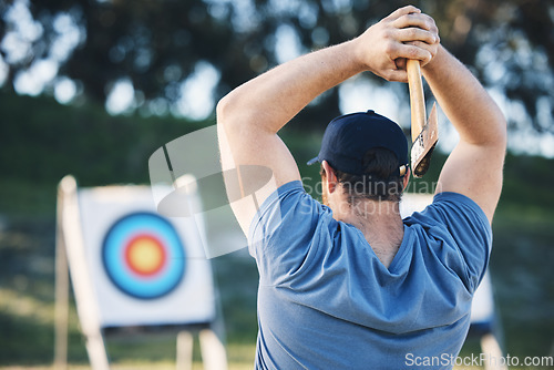 Image of Man axe throwing at sports range, archery training or practice with board circle for action, game and fitness. Strong person with weapon for tomahawk competition, gaming and park or field with target