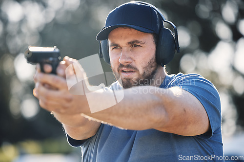 Image of Man, gun and learning to aim at shooting range outdoor for security target training. Face of person train with safety gear headphones for focus on sport competition with firearm weapon in hands