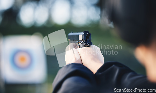 Image of Hands, gun and aim at shooting range target with weapon outdoor for security training. Person learning defence for safety and focus for sport competition or game with handgun gear and bullseye board