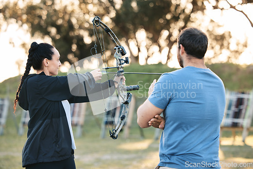 Image of Woman, archery and target training with an instructor on a field for hobby, aim and control. Arrow, practice and archer people together outdoor for hunting, precision and weapon, shooting competition