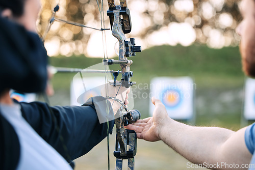 Image of Archer hands, coach and bow or arrow learning for archery competition, athlete focus challenge or girl training practice. Teacher, teaching and man coaching woman on sports, aim and target shooting