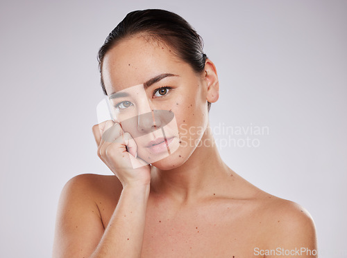 Image of Skincare, face and portrait of a woman in studio for beauty, dermatology and cosmetics for skin glow. Aesthetic asian model person with hand for makeup, mole and facial self care on grey background