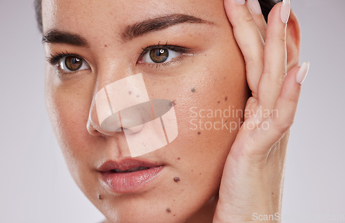 Image of Beauty, face and skincare of a woman in studio for makeup, dermatology and cosmetics for skin glow. Aesthetic asian model person with hand to show mole and facial self care for health and wellness