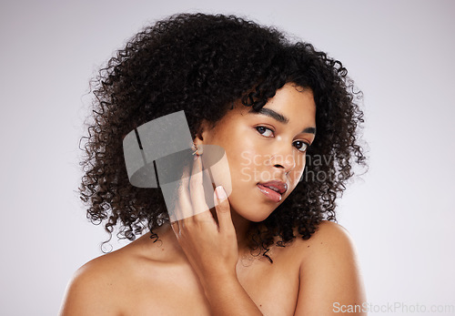 Image of Skincare, looking and portrait of a black woman feeling face isolated on a grey studio background. Beauty, African and model touching skin to check for acne, grooming and routine on a backdrop