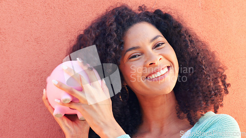 Image of Piggy bank, cash and savings with a black woman listening to money in a pig outside on a pink wall background. Happy, smile and success with a young female confident with her finance and budget