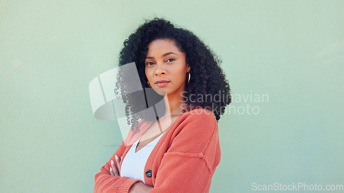 Image of Black woman, confident beauty and young model pose for portrait with afro hair on green background. African girl in orange sweater, fold arms with cool serious face and casual fashion lifestyle
