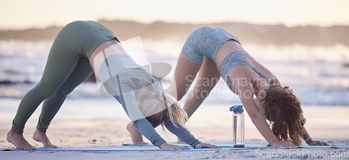 Image of Woman, friends and yoga stretching on beach for spiritual wellness, zen or workout together in nature. Women yogi in warm up stretch, svanasana pose or pilates for healthy exercise on ocean coast