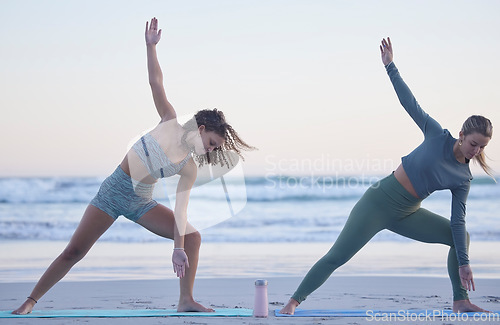 Image of Woman, friends and yoga stretching on beach for spiritual wellness, zen or workout together in nature. Women yogi in warm up stretch, trikonasana pose or pilates for healthy exercise on ocean coast