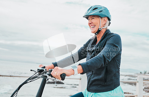 Image of Senior woman, bike and smile in cycling by the beach for fun activity or travel in the city. Happy elderly woman smiling and enjoying cruise on bicycle for traveling, trip or fitness by ocean coast