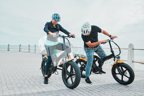 Image of Mature couple, electrical or checking bike by beach in bonding transportation, clean energy or sustainability city travel. Ebike, electricity or eco friendly bicycle for elderly man or cycling woman