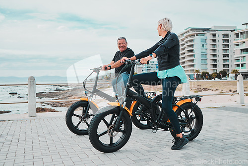 Image of Mature couple, electrical and bike by ocean, beach or sea in bonding transportation, clean energy or sustainability travel. Ebike, electricity and eco friendly bicycle for happy man or cycling woman